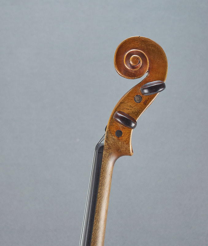 The scroll of an antique, handmade Dresden Violin (side view).