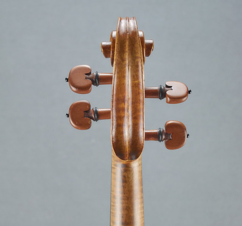 The scroll of an antique, handmade Mirecourt Violin (1890) with stunning flamed maple (back view).