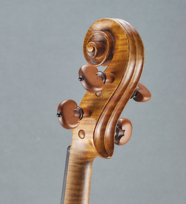 The scroll of an antique, handmade Mirecourt Violin (1890) with stunning flamed maple (back view).